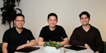 Three men in black shirts sit around a circular table